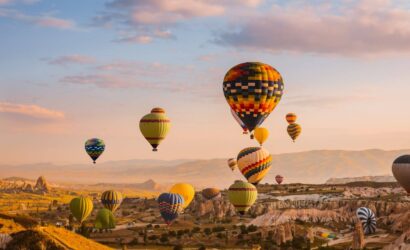 Colorful hot air balloons drifting over Cappadocia's Goreme Valley at sunrise, showcasing stunning rock formations.