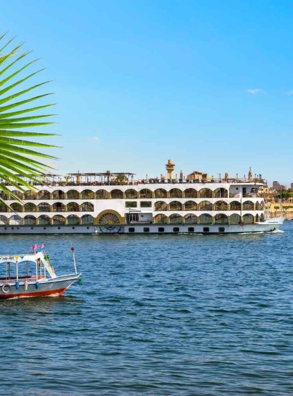 A scenic Nile River cruise with a traditional boat in the foreground and a luxury cruise ship passing near ancient Egyptian temples in the background.