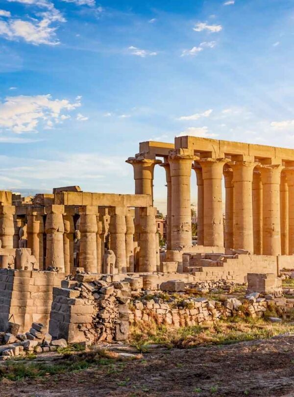 The Luxor Temple in Egypt, featuring towering stone columns and ancient ruins, bathed in warm golden sunlight during sunset.