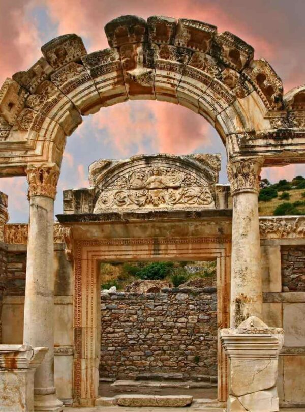 The ancient Temple of Hadrian in Ephesus, Turkey, featuring detailed stone carvings and arched columns at sunset.