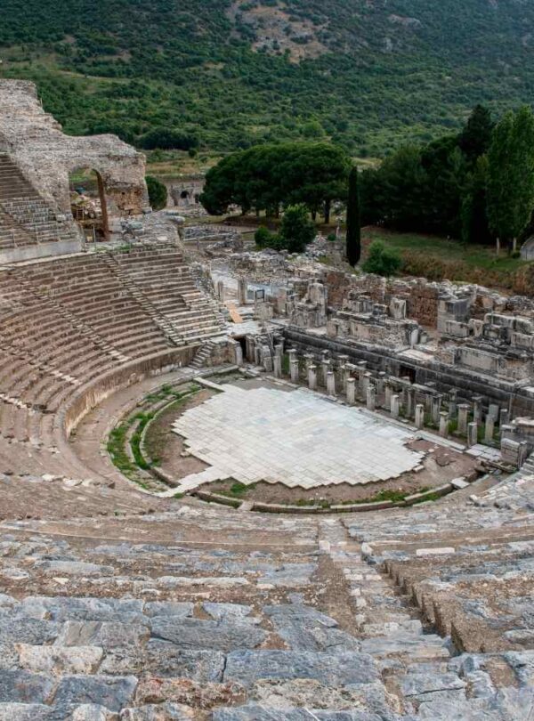 Ancient Grand Theater of Ephesus in Turkey, featuring tiered stone seating and a large stage area surrounded by ruins.