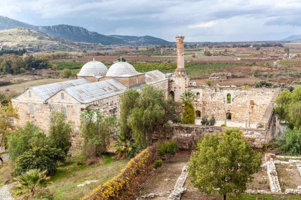 The Isa Bey Mosque in Selçuk, Turkey, an ancient stone structure with domed roofs and a partially ruined minaret.