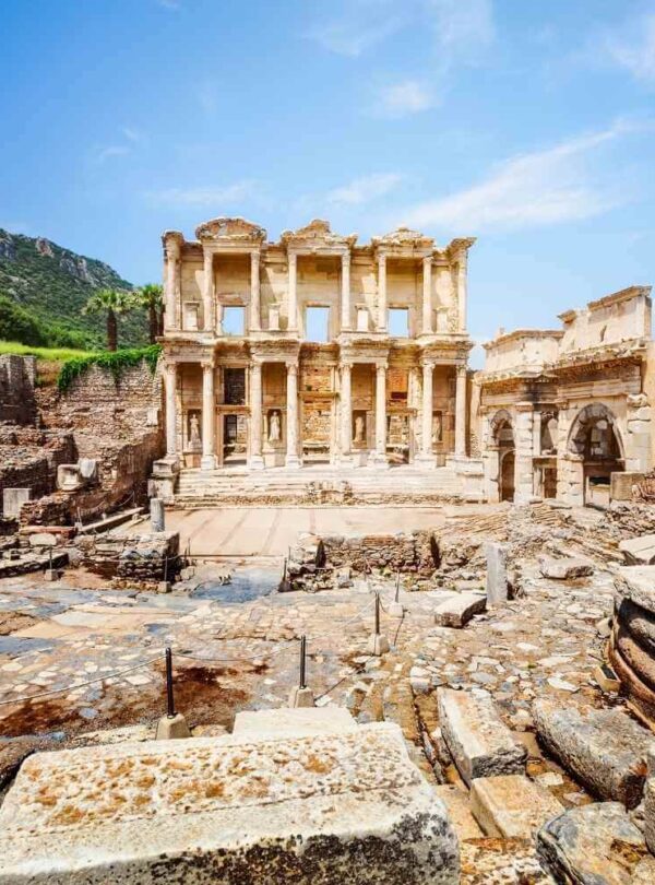 The ruins of the Celsus Library in Ephesus, Turkey, with towering columns and stone carvings under a bright sky.