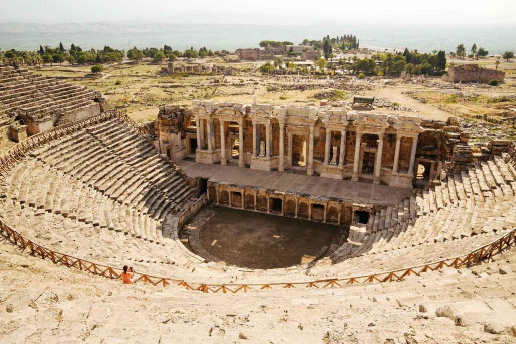 Ruins of the ancient Roman theatre in Hierapolis, Turkey, featuring tiered seating and a grand stage with columns.