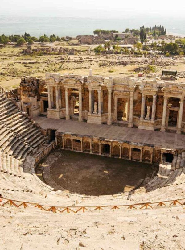 Ruins of the ancient Roman theatre in Hierapolis, Turkey, featuring tiered seating and a grand stage with columns.