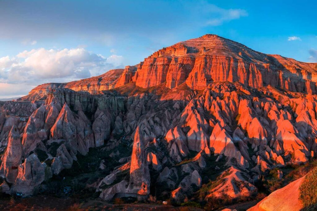 Breathtaking view of the Red Valley in Cappadocia at sunset, illuminating the rugged rock formations in warm hues.