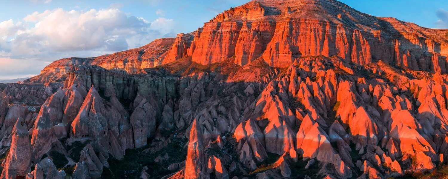 Breathtaking view of the Red Valley in Cappadocia at sunset, illuminating the rugged rock formations in warm hues.