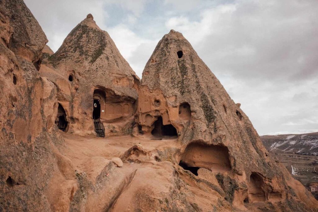 Ancient rock-carved caves and pointed structures in Cappadocia, Turkey, showcasing unique geological formations.