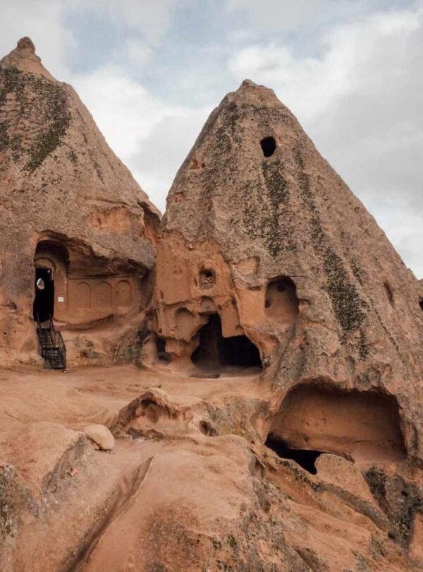 Ancient rock-carved caves and pointed structures in Cappadocia, Turkey, showcasing unique geological formations.