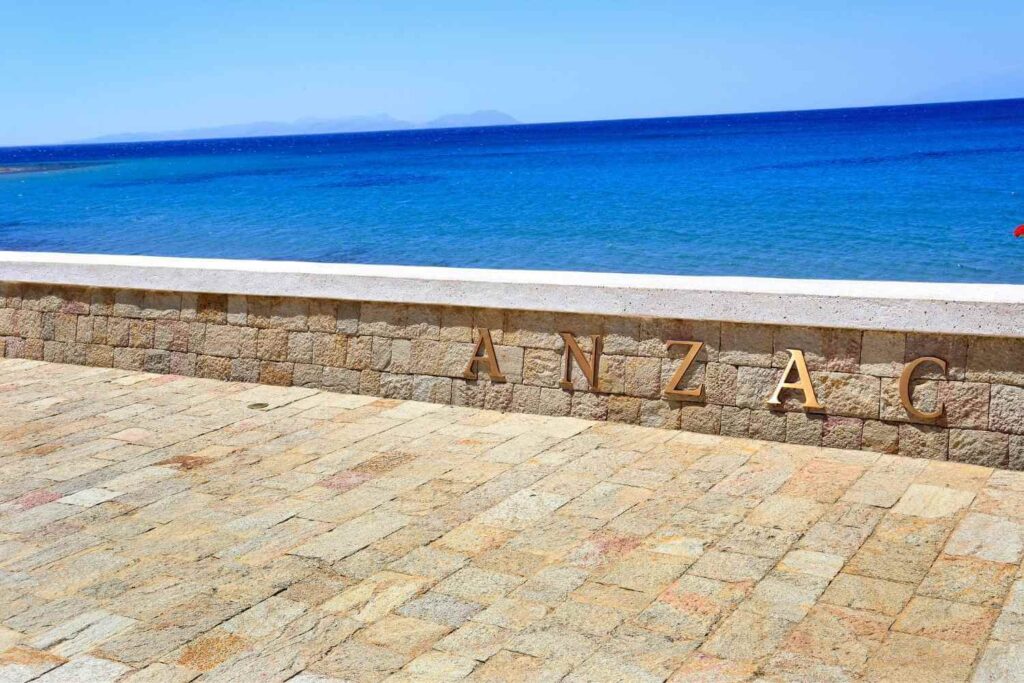 ANZAC stone memorial overlooking the serene blue ocean, with a paved stone area and clear sky, reflecting historical significance.