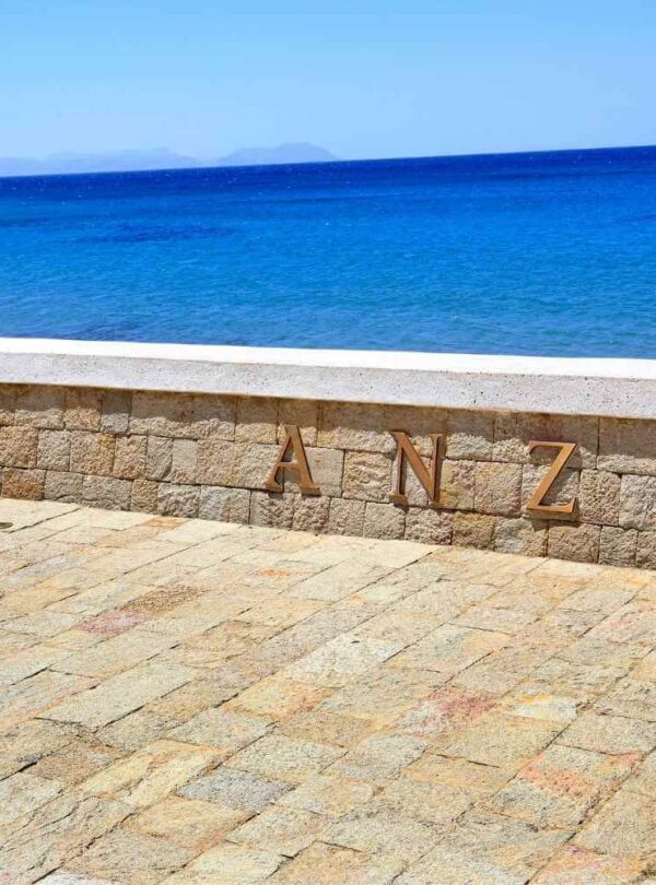 ANZAC stone memorial overlooking the serene blue ocean, with a paved stone area and clear sky, reflecting historical significance.