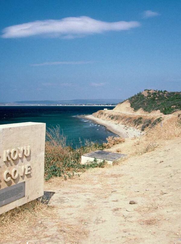 Stone monument at Anzac Cove overlooking a curved coastline, with clear blue sea and sky in the background.