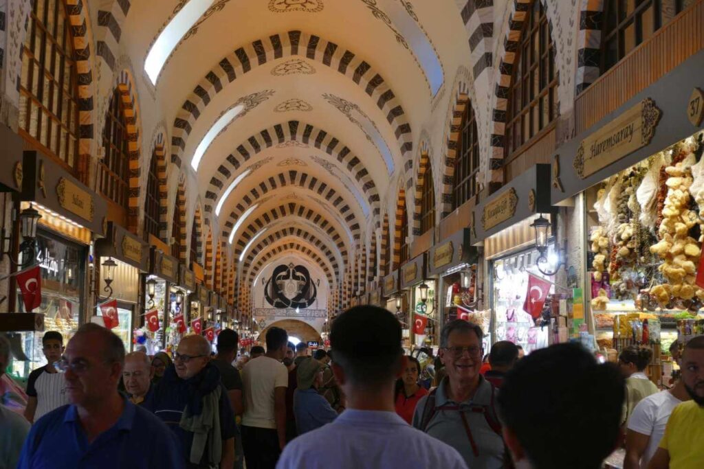 Visitors explore the Spice Market's arched hallways, lined with Turkish flag-adorned shops selling spices, dried goods, and souvenirs.