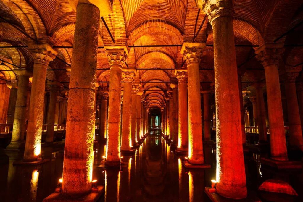 Interior of the Basilica Cistern in Istanbul, featuring illuminated columns and arched ceilings with a reflective water surface.