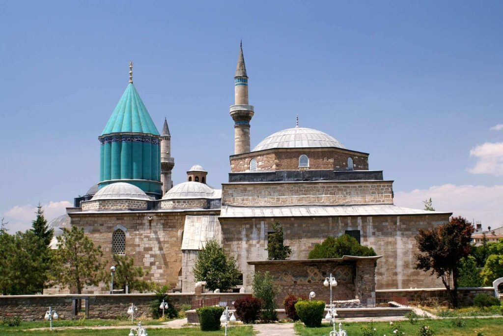 Exterior view of the Mevlana Museum in Konya, Turkey, featuring its iconic turquoise dome and historical architecture.