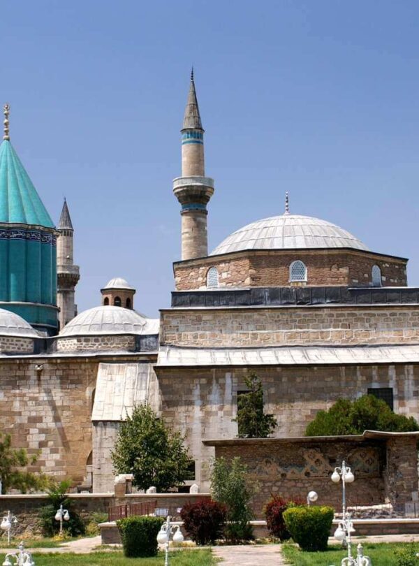 Exterior view of the Mevlana Museum in Konya, Turkey, featuring its iconic turquoise dome and historical architecture.