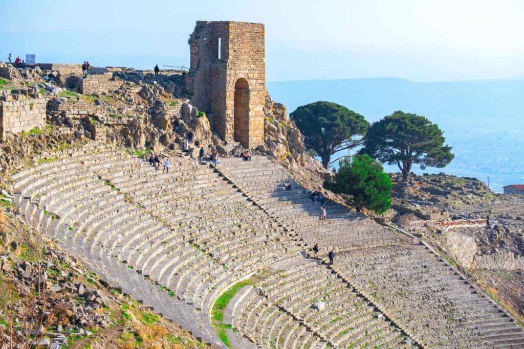 Pergamon Hellenistic Theater in Turkey, with steep stone seating carved into the hillside and a tower overlooking the landscape.