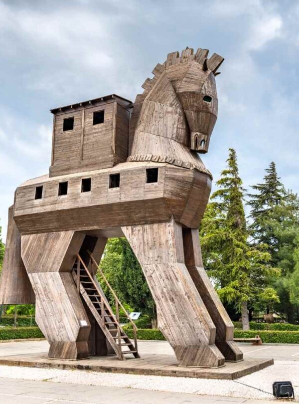 Wooden Trojan Horse replica in the ancient city of Troy, surrounded by greenery and a clear sky.