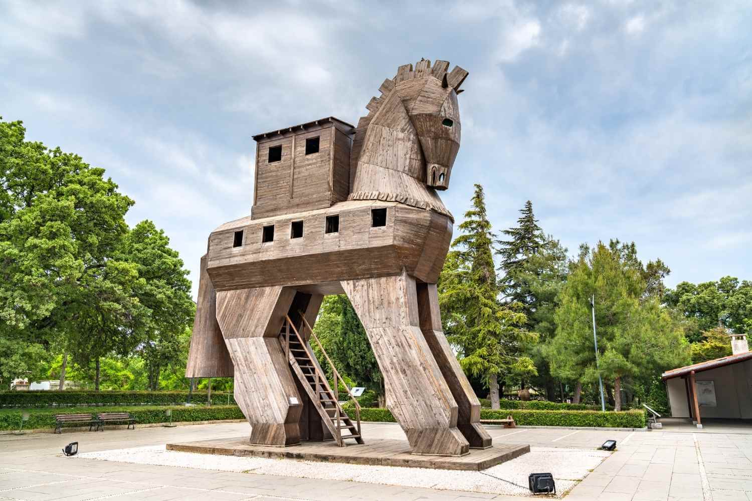 Wooden Trojan Horse replica in the ancient city of Troy, surrounded by greenery and a clear sky.