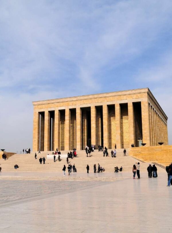 Wide-angle view of the Mausoleum of Atatürk in Ankara, Turkey, showcasing its grand columns and large courtyard with visitors exploring.