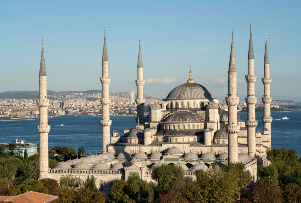 The Blue Mosque in Istanbul with six minarets, a grand dome, and scenic Bosphorus views, surrounded by lush greenery.