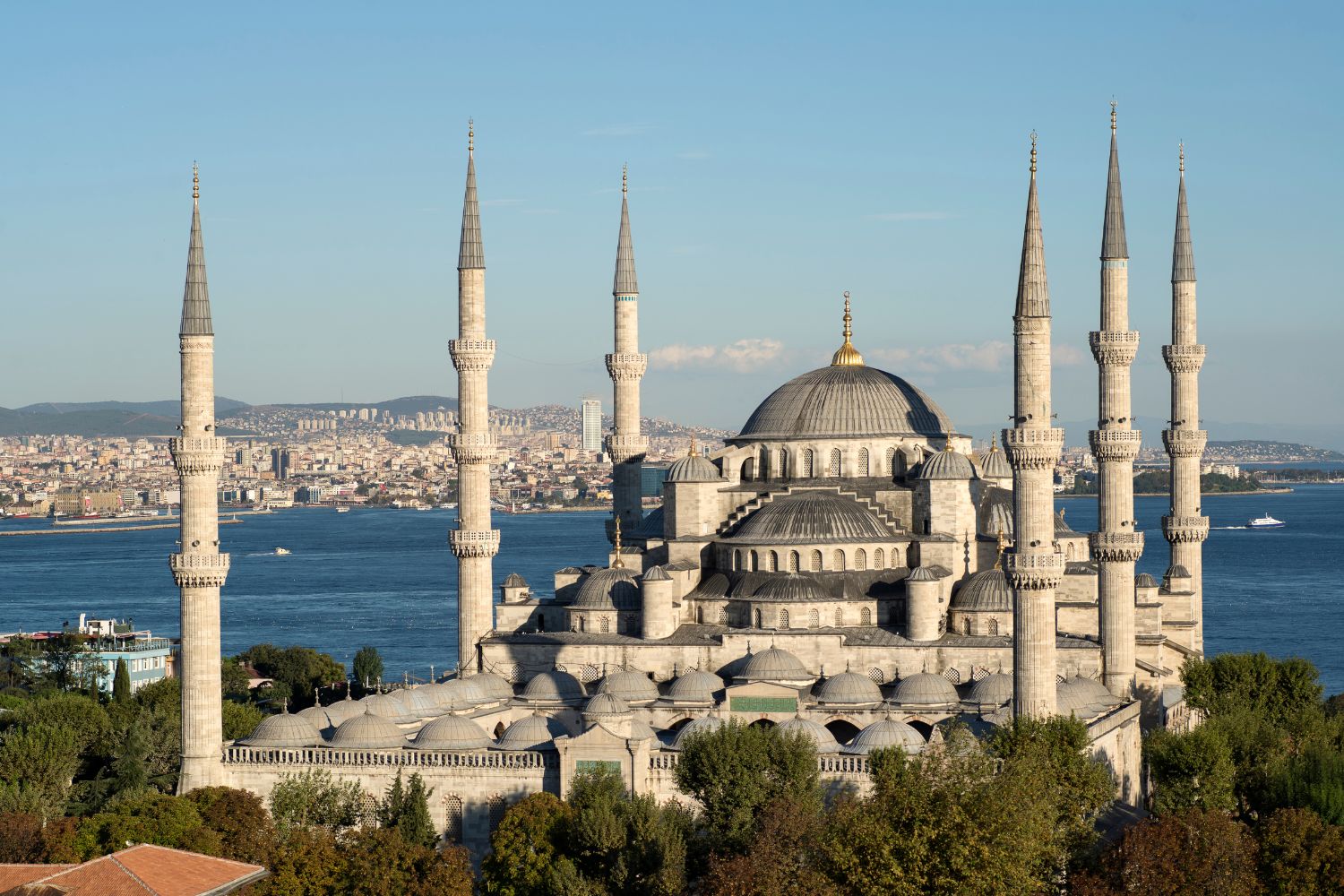 The Blue Mosque in Istanbul with six minarets, a grand dome, and scenic Bosphorus views, surrounded by lush greenery.